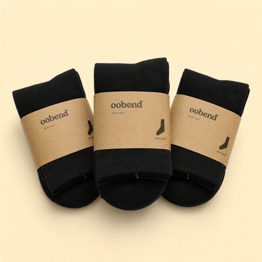 Three pairs of black socks with brown labels on a beige background